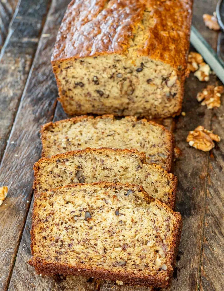 a sliced up banana nut bread on a wooden board.