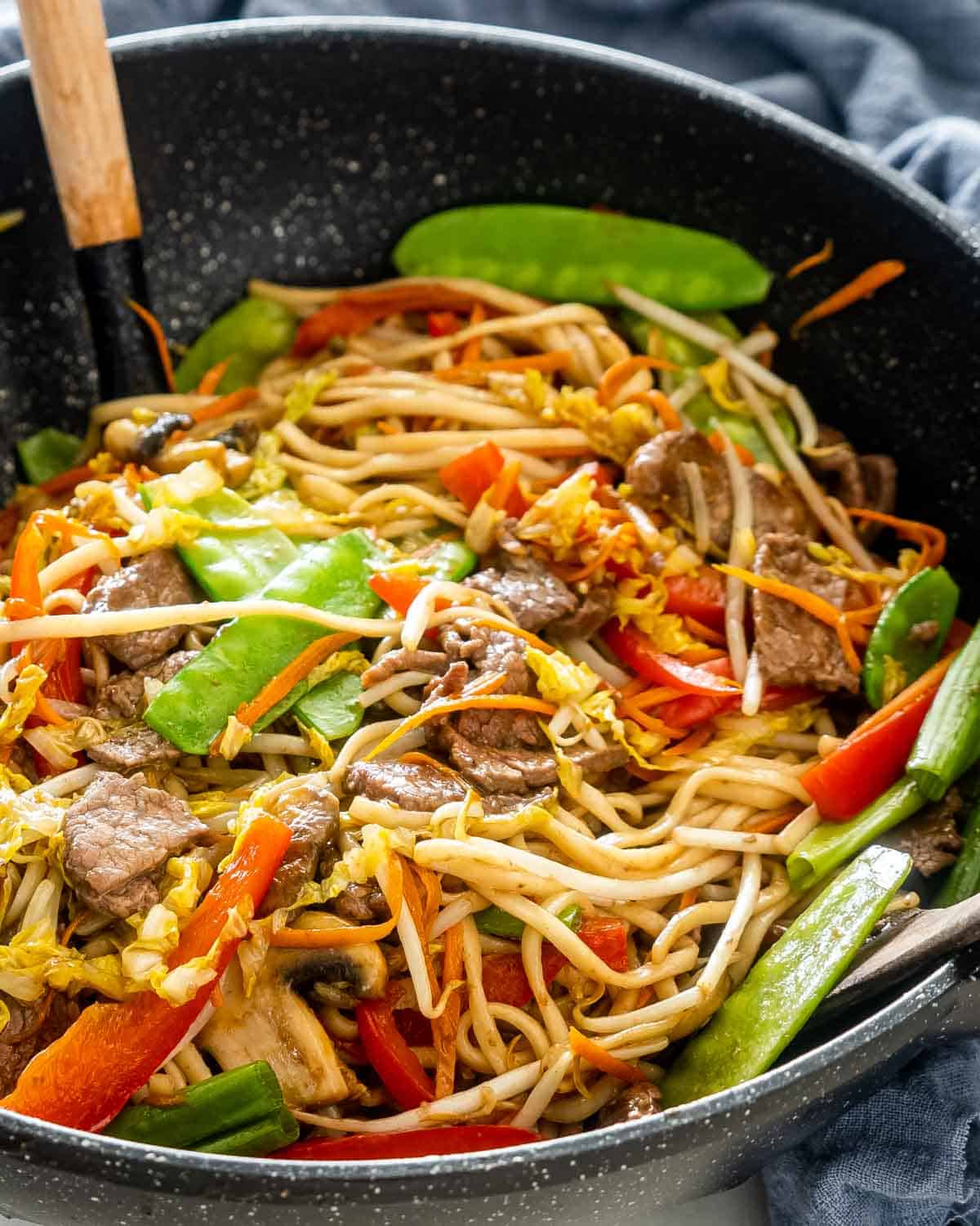 beef lo mein in a black wok.