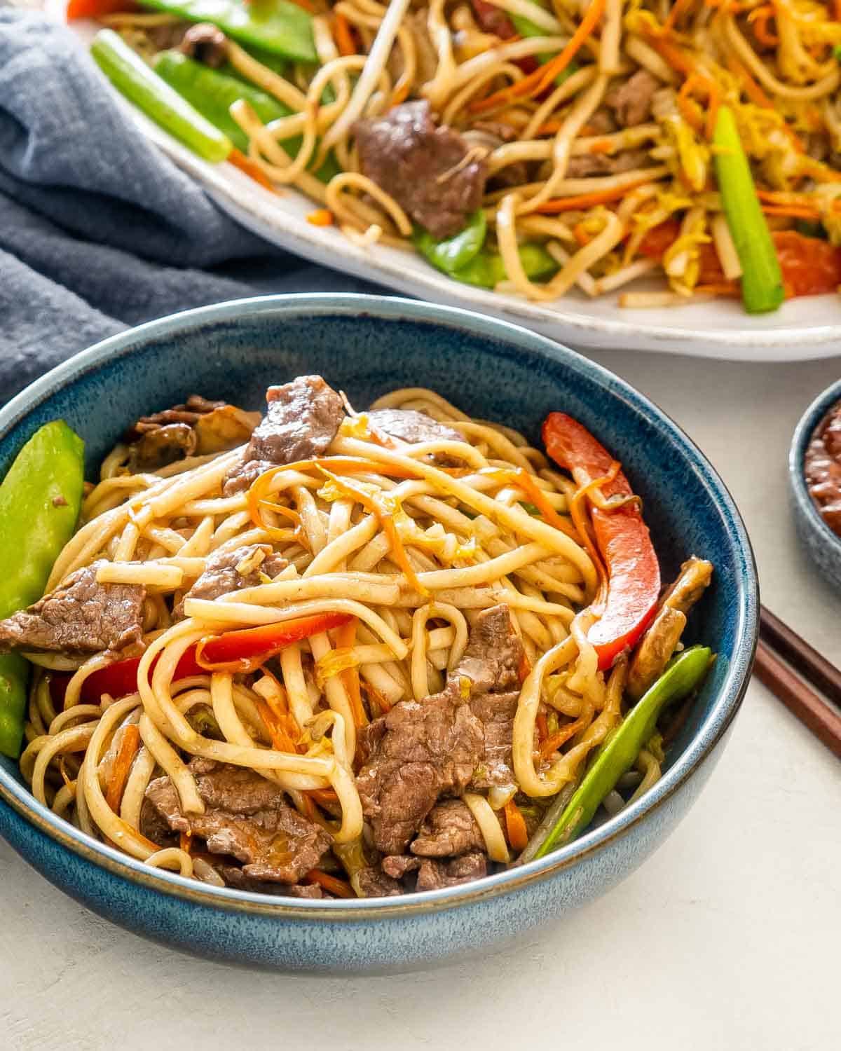 freshly made beef lo mein in a blue bowl.