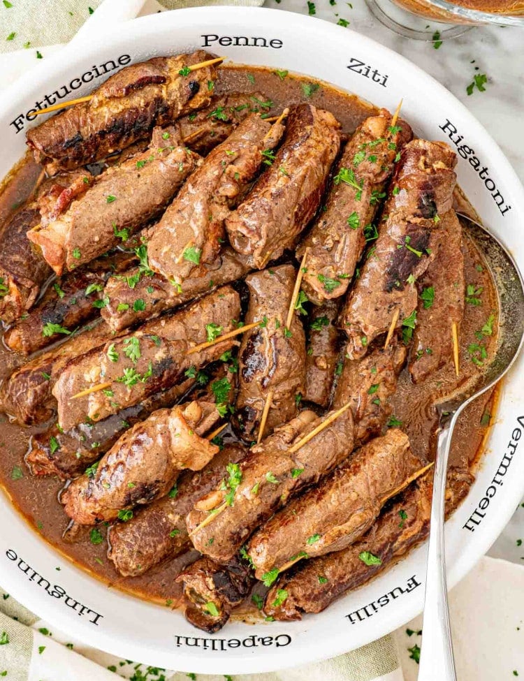 beef rouladen in a large serving bowl with a serving spoon.