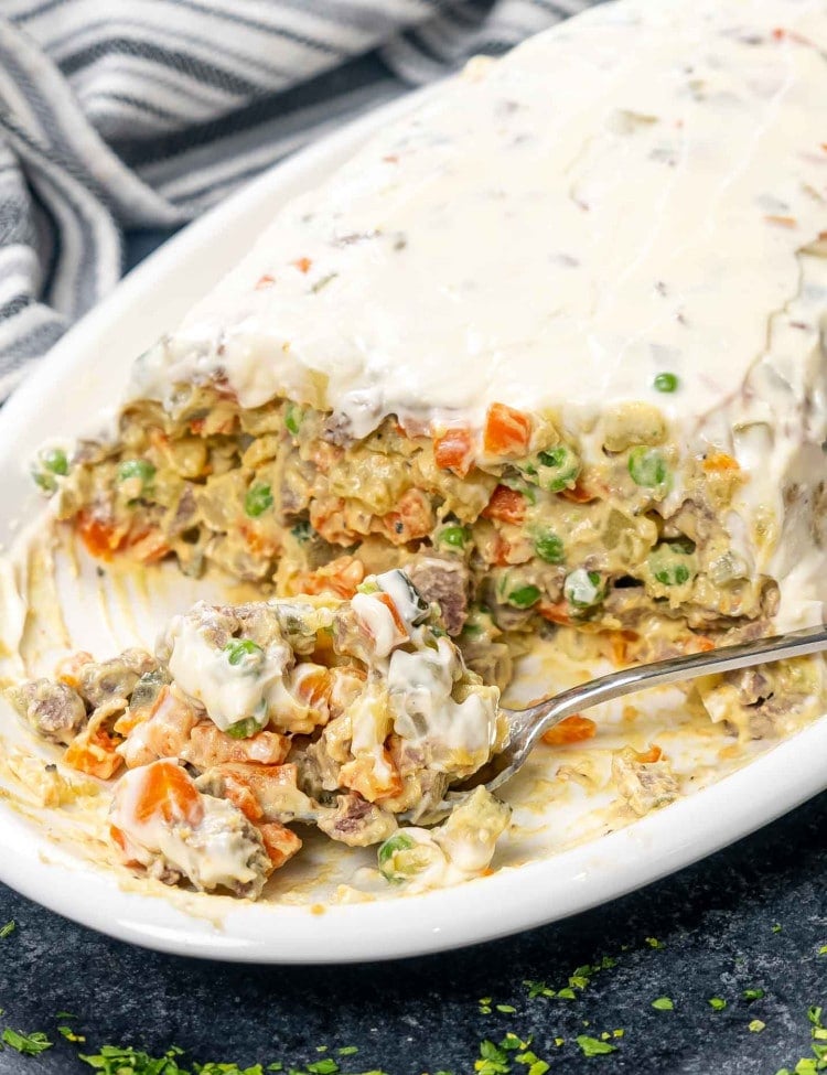 beef salad (salata de beouf) on a white serving bowl topping with mayonnaise.