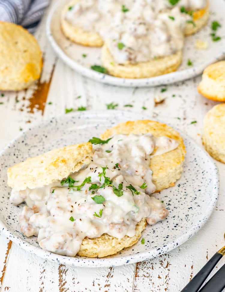 biscuits and gravy on a white little plate garnished with parsley.