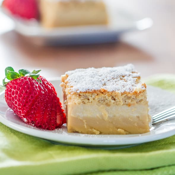 a slice of butterscotch magic cake on a plate with a fresh strawberry as garnish