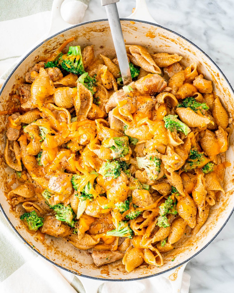 overhead shot of cheesy chicken broccoli pasta in a pot with a serving spoon taking a scoop