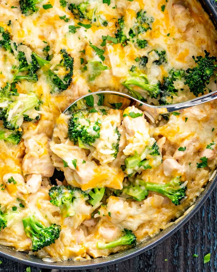 a serving spoon inside a skillet with chicken broccoli rice casserole.