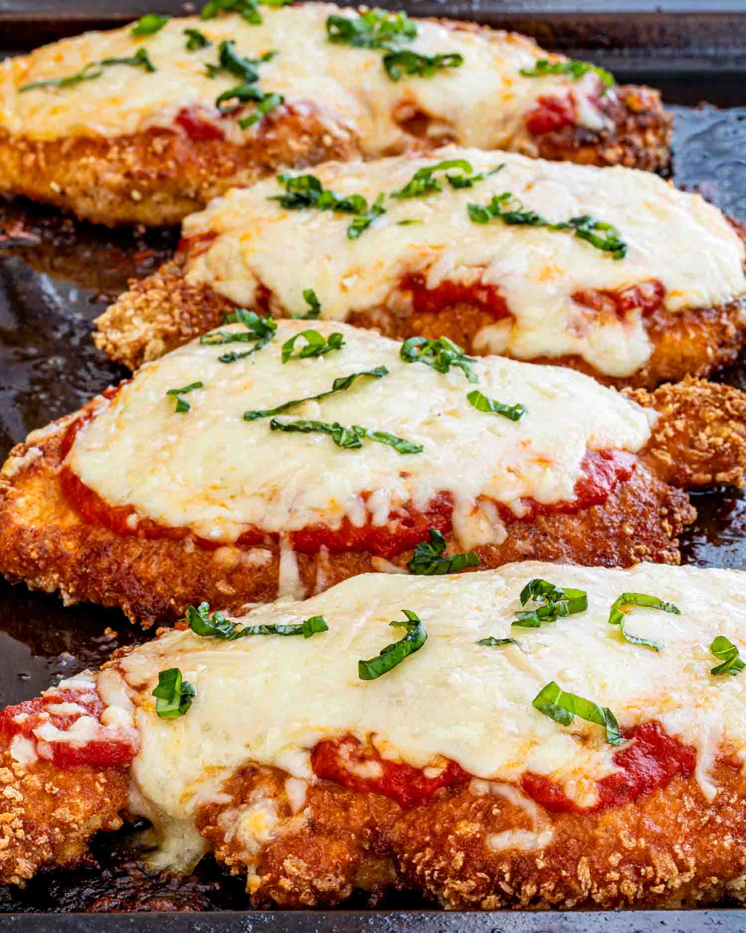 chicken parmesan fresh out of the oven on a baking sheet.