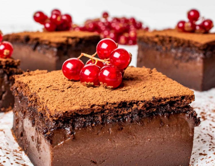 chocolate magic cake slices sprinkled with cocoa powder and garnished with garnish.