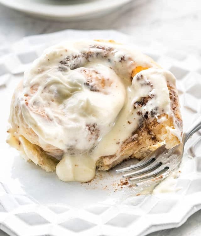 side view shot of a cinnamon bun with a bite taken out of it on a plate