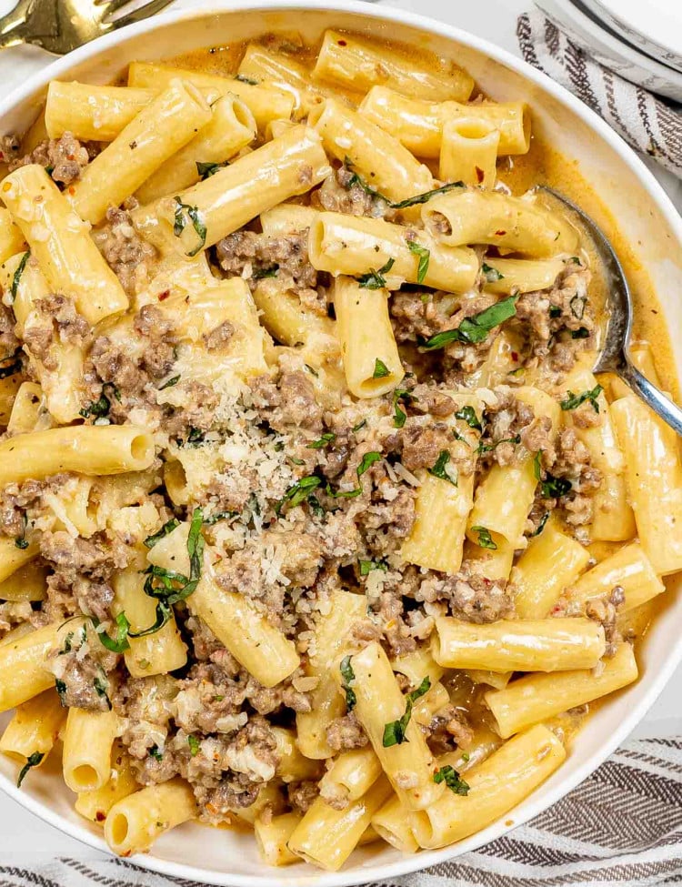 creamy italian sausage pasta in a white serving bowl.