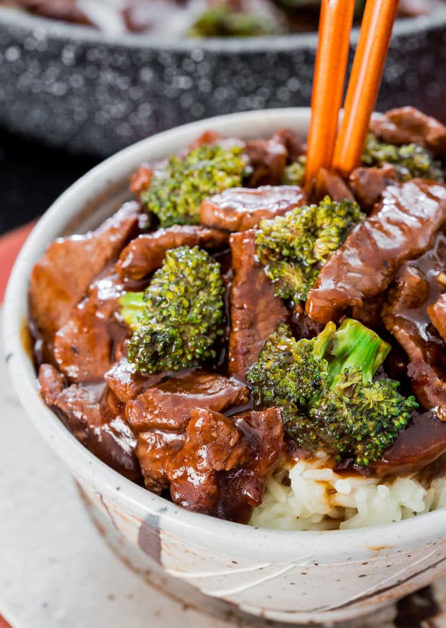 beef and broccoli on a bed of rice in a bowl