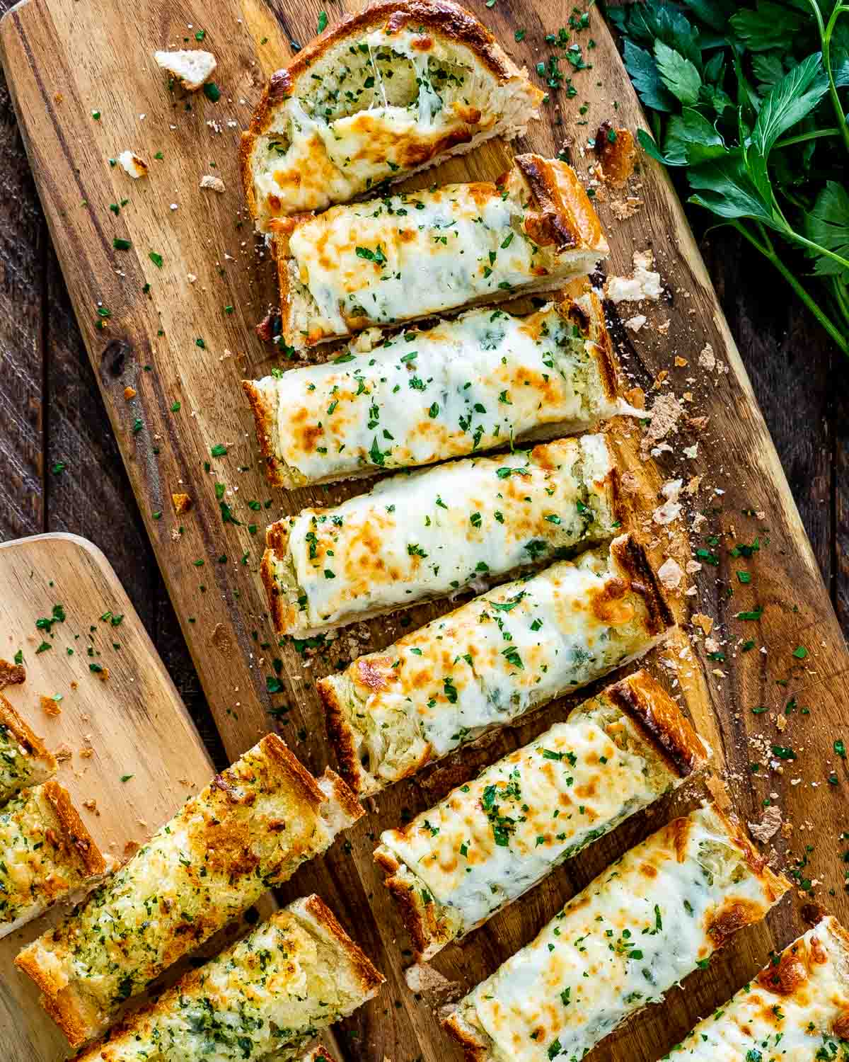 cheesy garlic bread fresh out of the oven sliced on a cutting board.