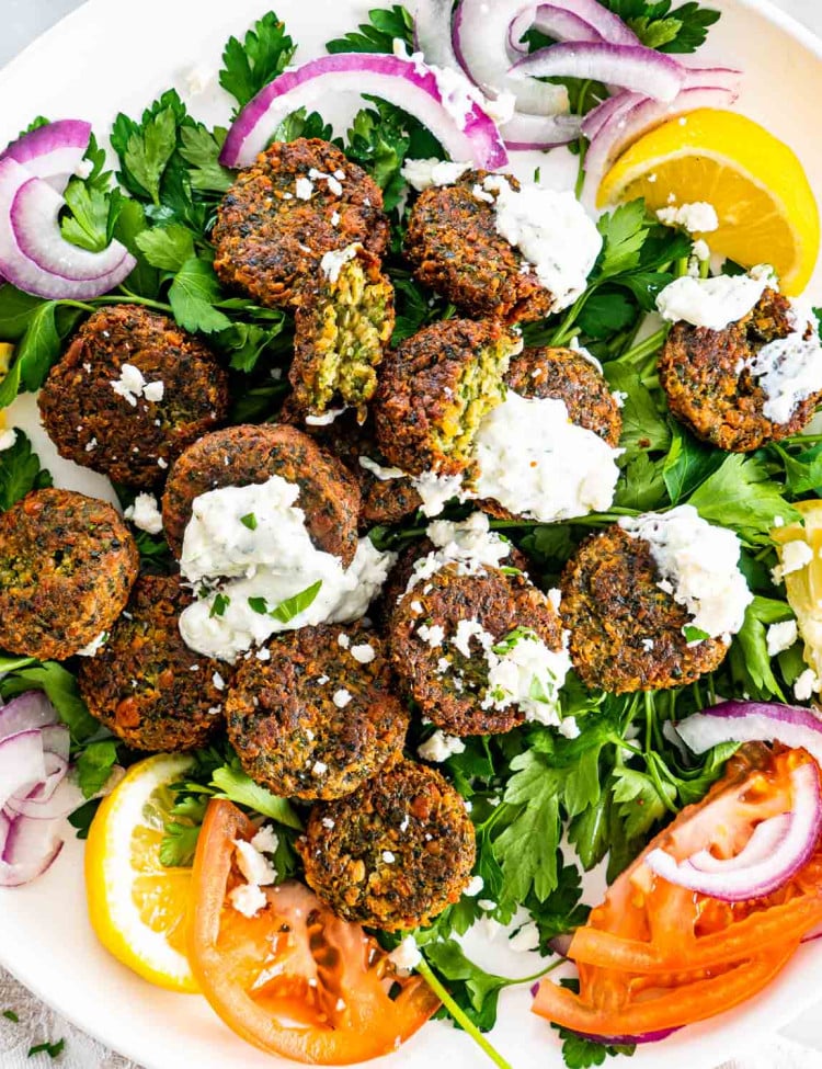 overhead of falafel on a plate with tzatziki, feta, tomatoes and onions.