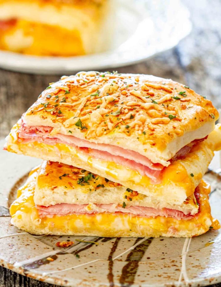 a ham and cheese pocket sliced in half on a plate.