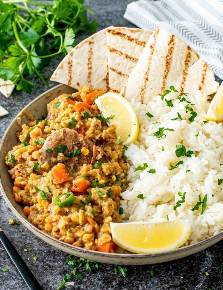 indian lentil curry with rice and lemon wedges in a bowl.