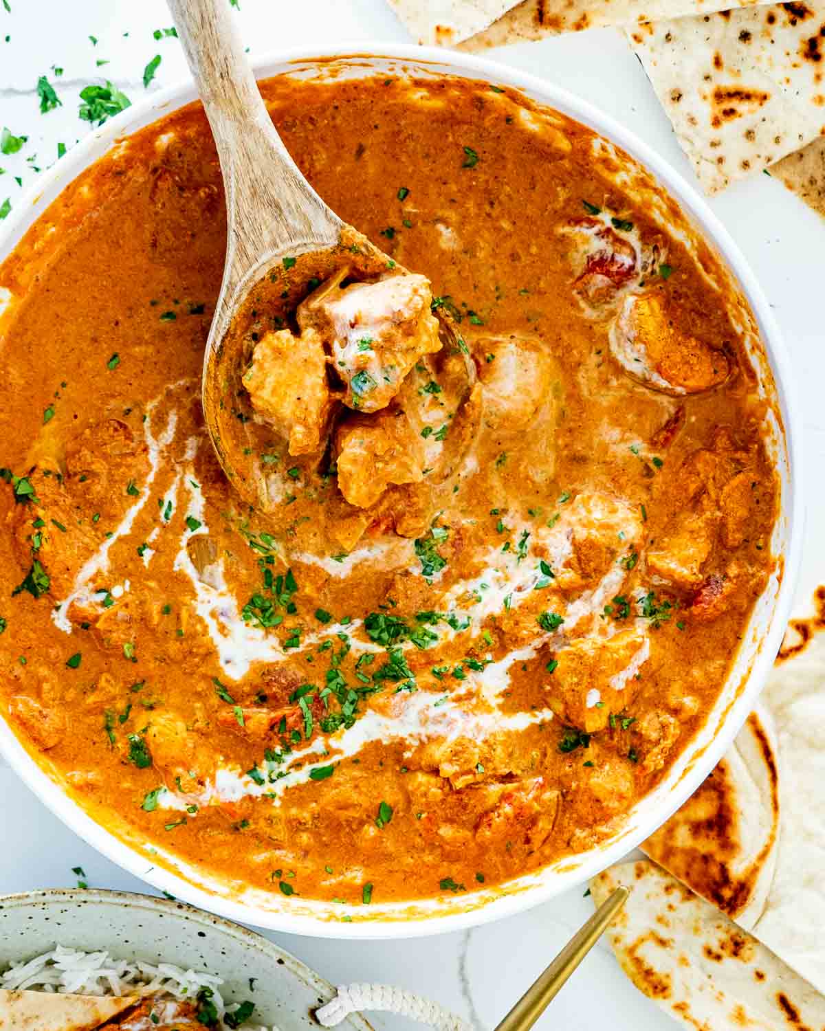 chicken tikka masala made in the instant pot in a white bowl with a wooden spoon inside.