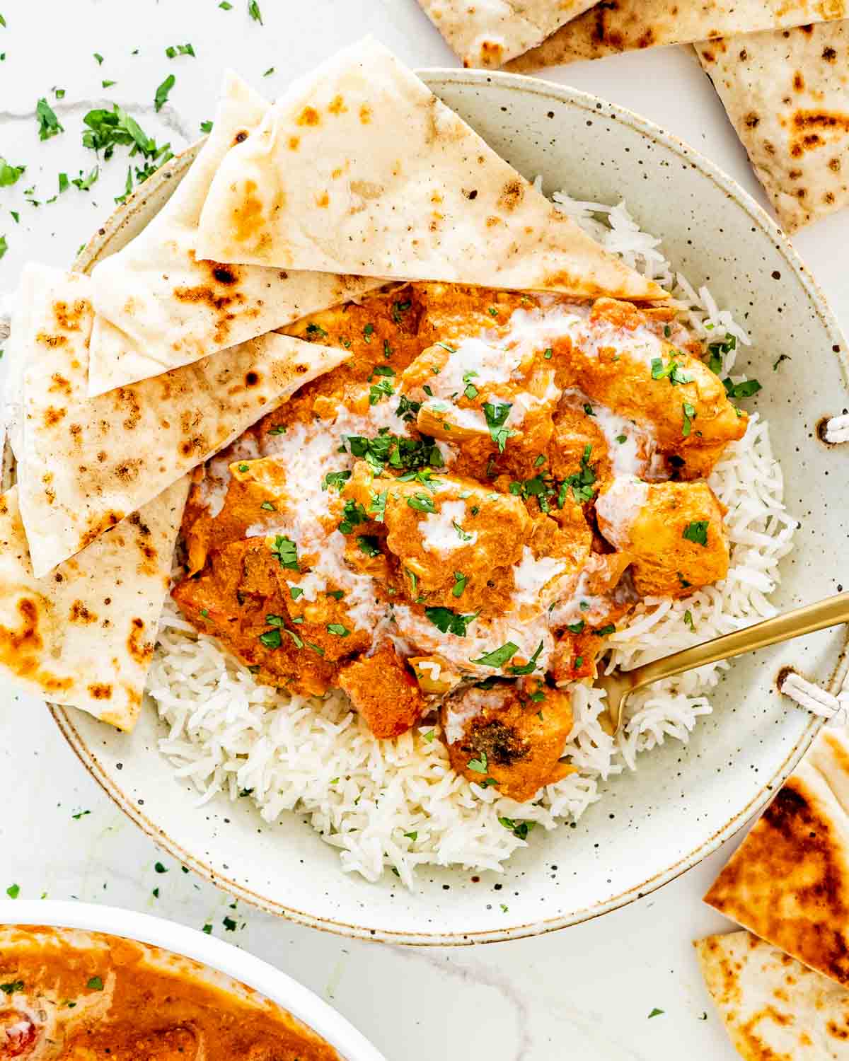 chicken tikka masala in a plate with rice and garnished with cilantro.