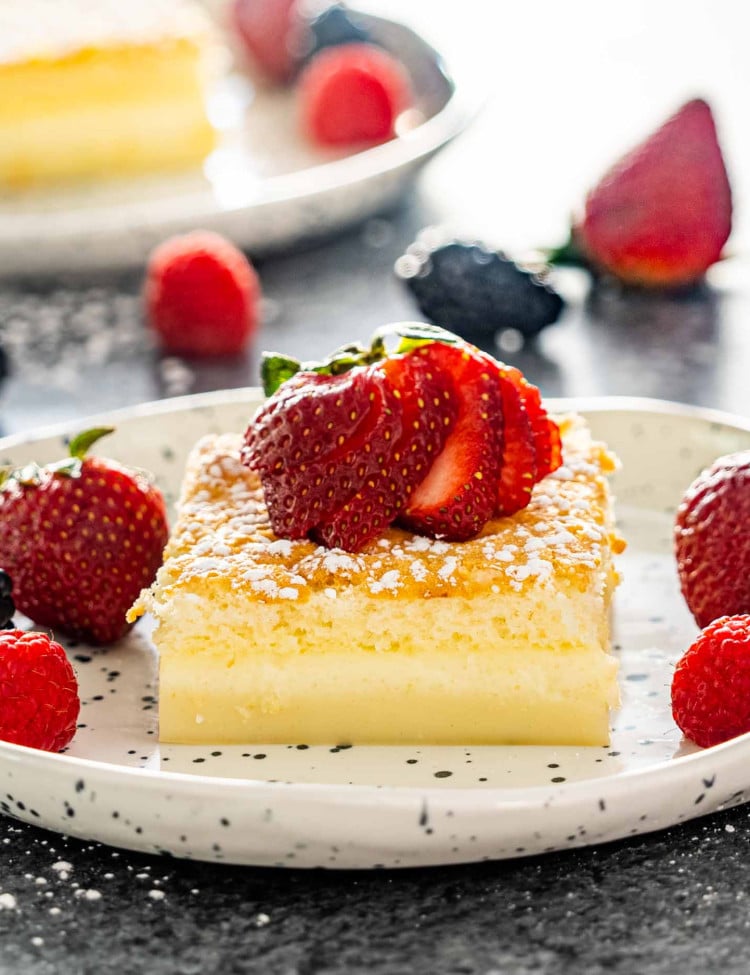 magic cake on a plate garnished with powdered sugar and a strawberry.