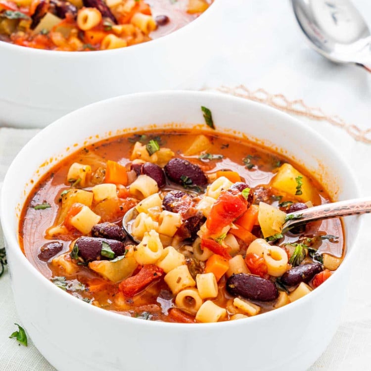 a spoon lifting minestrone soup from the bowl