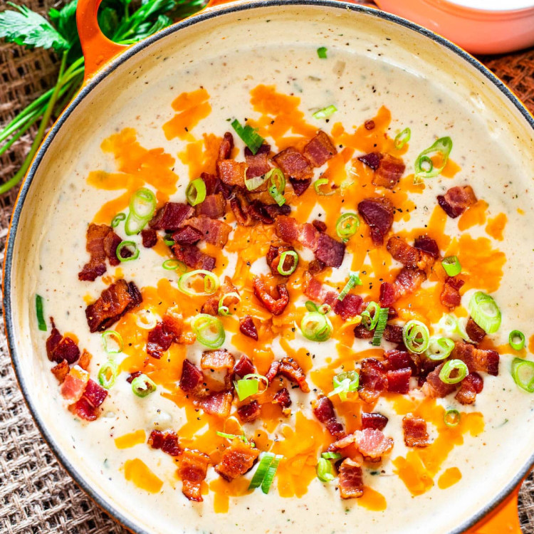overhead shot of a pot of potato soup topped with cheese, chopped bacon and sliced green onions