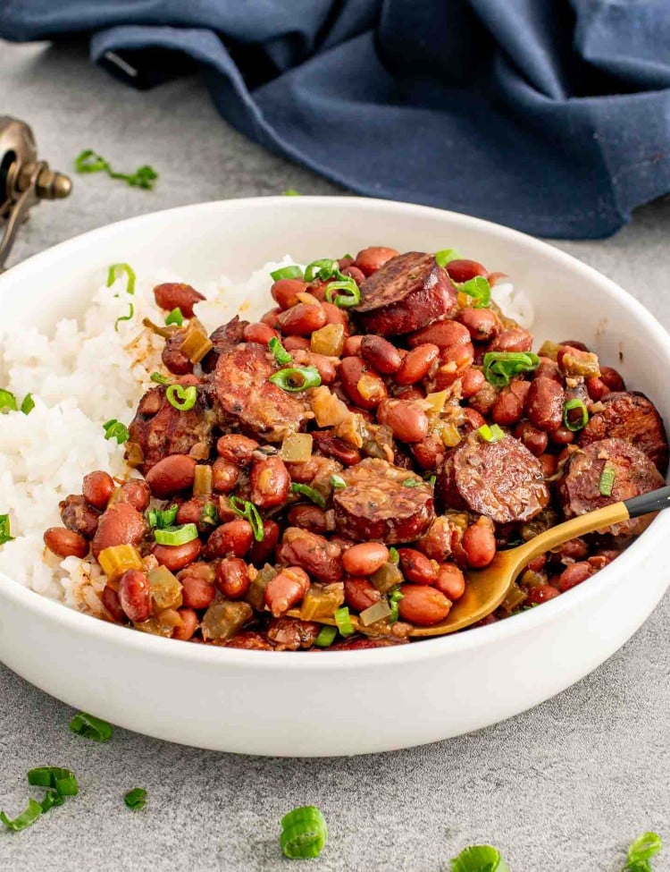 red beans and rice in a white bowl garnished with green onions.