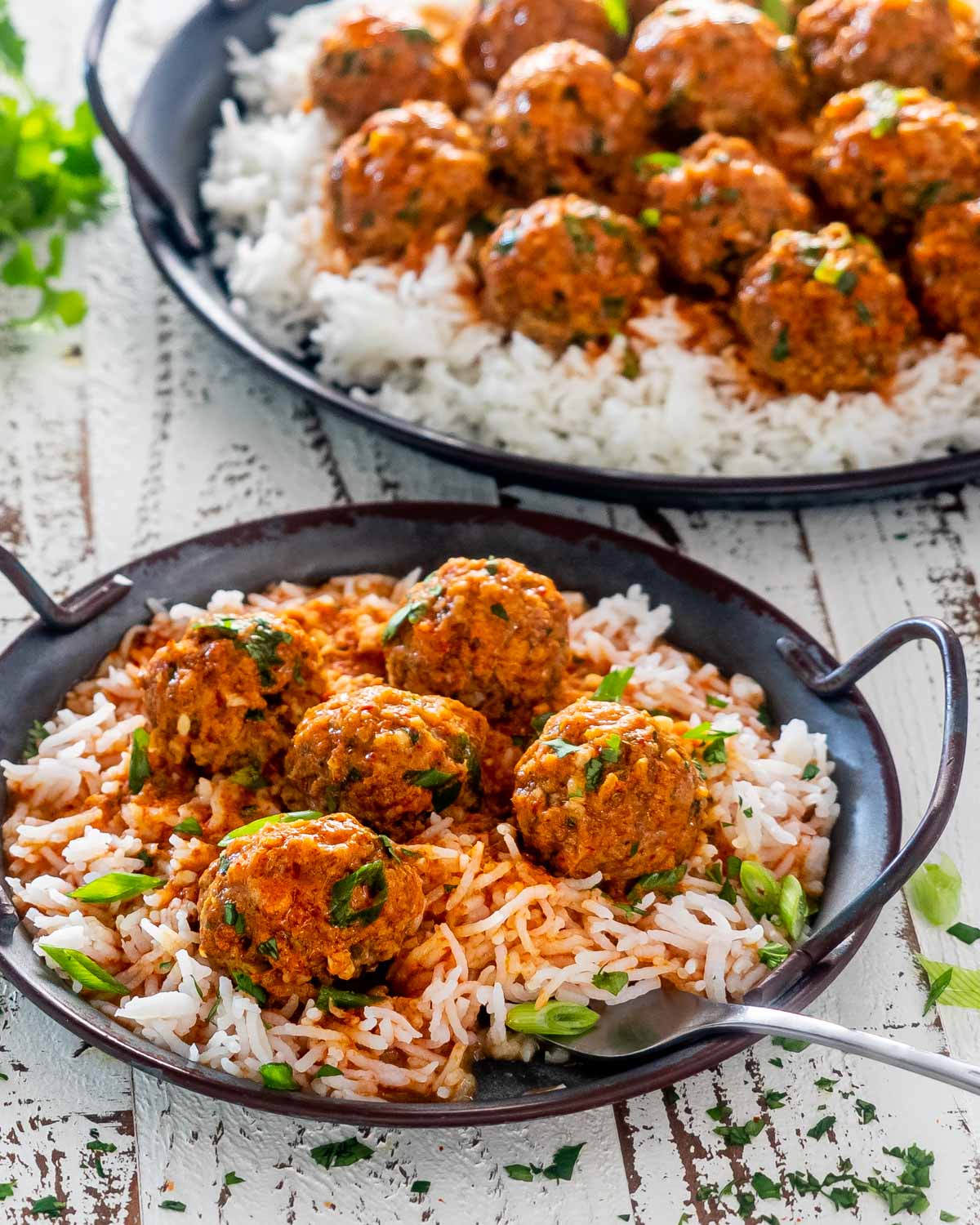 a serving of red curry turkey meatballs over a bed of rice in a metal plate.