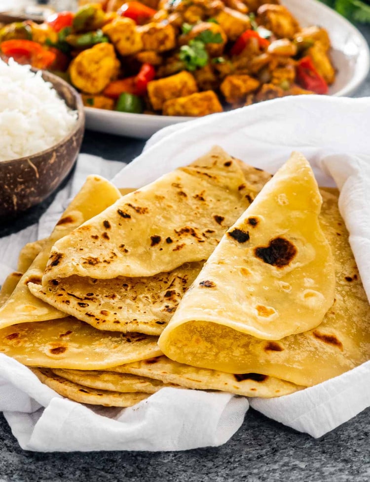 a stack of roti wrapped in a clean kitchen towel.