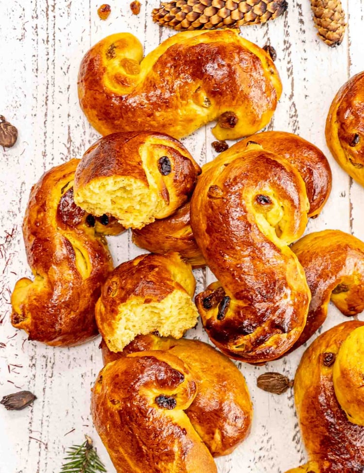 a few freshly baked saffron buns on a white wooden board.