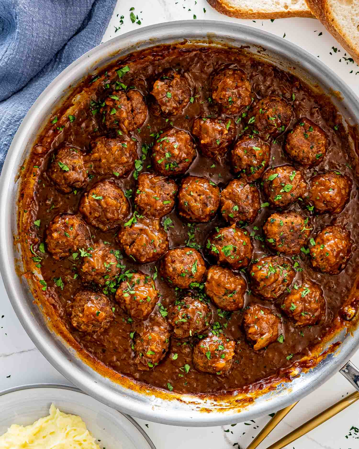 salisbury steak meatballs with gravy in a skillet garnished with parsley.
