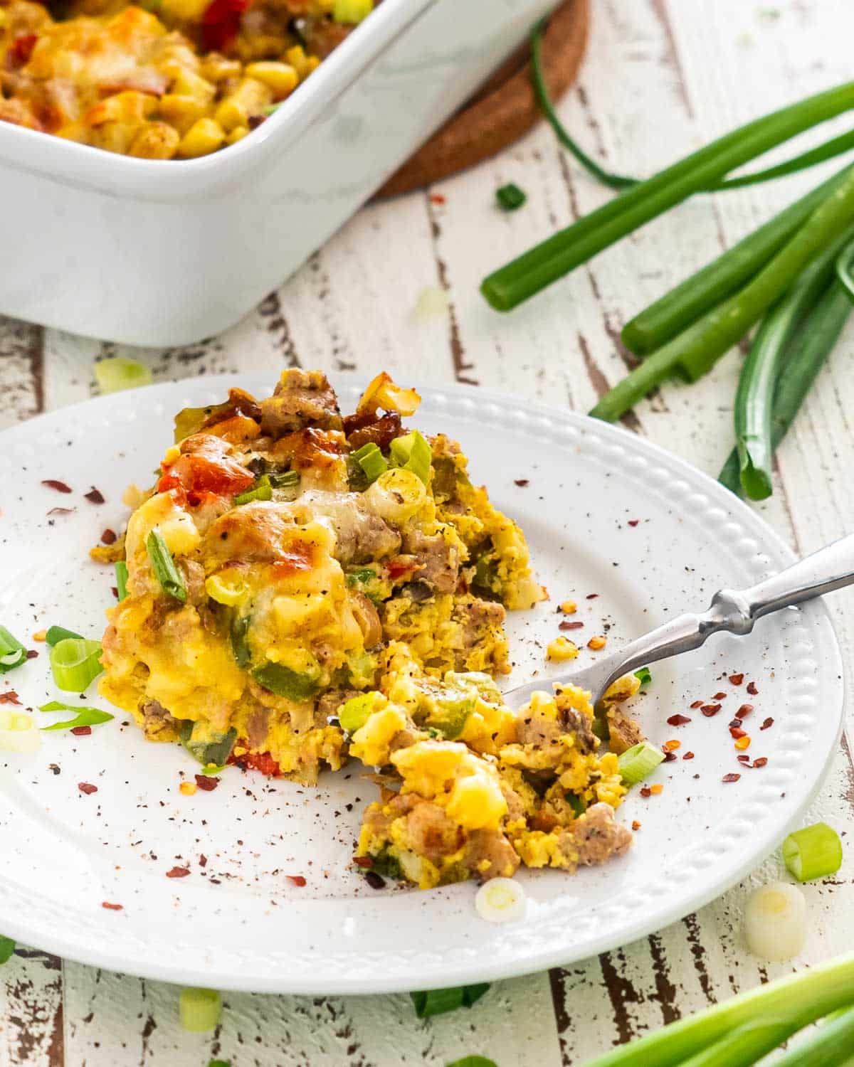 a slice of sausage potato breakfast casserole on a white plate.