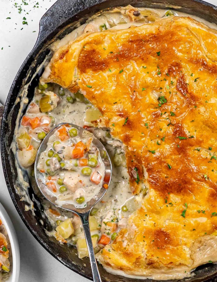 skillet chicken pot pie in a cast iron skillet with a serving taken out.